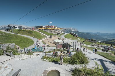 Ellmi's Zauberwelt Ein malerischer Bergort mit vielen Besuchern und klar blauem Himmel. Die Umgebung ist grün und einladend, ideal für Outdoor-Aktivitäten.