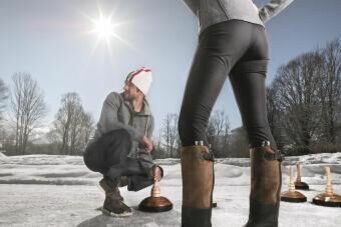 Eisstockschießen am Schwarzsee Zwei Personen beim Eisstockschießen auf einer Eisfläche im Freien bei Sonnenschein.