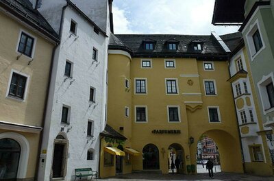 Pfleghof Ein malerischer Platz mit bunten Gebäuden und einem gelben Haus mit einem Tor. Die Architektur zeigt einen typischen, charmanten Stil.