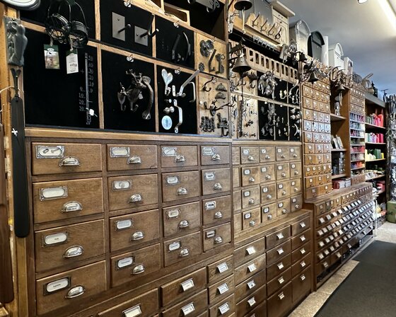 Innenansicht eines Ladens mit hohen Holzschränken voller kleiner Schubladen und Metallbeschlägen an der Wand.