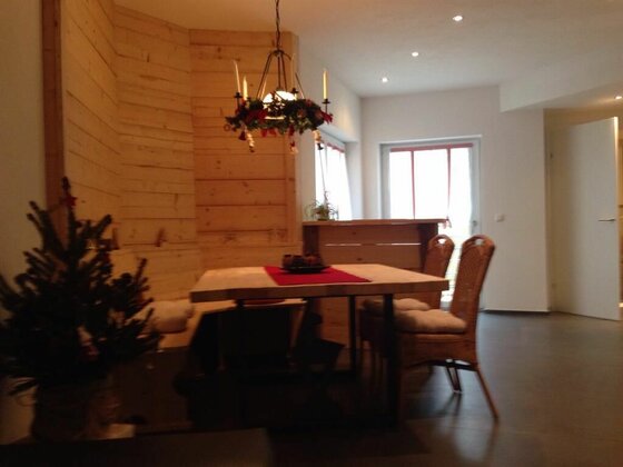 Moderner Essbereich mit Holztisch, Rattanstühlen und holzverkleideter Wand.