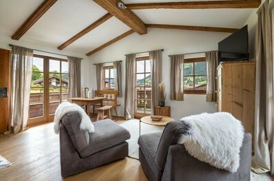 Wohnraum Ski In/Out Asten Wohnbereich eines Apartments mit zwei Sesseln, Holztisch, Eckbank und Sichtbalken an der Decke.