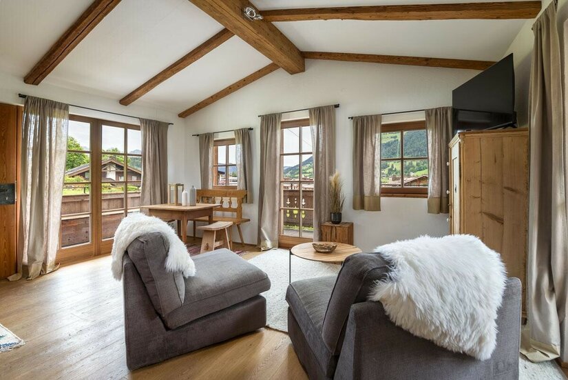 Wohnraum Ski In/Out Asten Wohnbereich eines Apartments mit zwei Sesseln, Holztisch, Eckbank und Sichtbalken an der Decke.