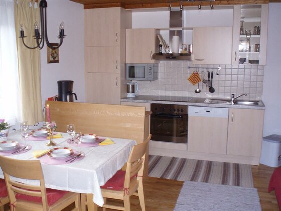 Moderne Küchenzeile aus hellem Holz mit angrenzendem Esstisch und Stühlen.