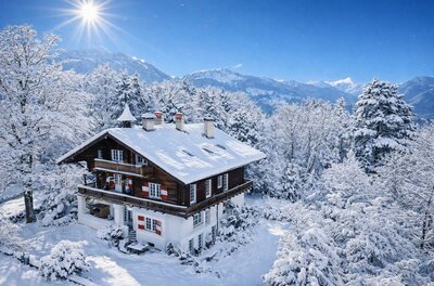 Ein charmantes Holzhaus in einer verschneiten Landschaft. Die Bäume und der Himmel sind klar und strahlend.