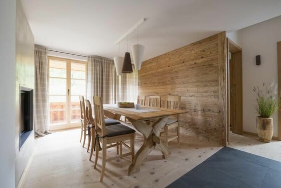 Moderner Essbereich mit Holztisch, Stühlen und einer Wandverkleidung aus Altholz.