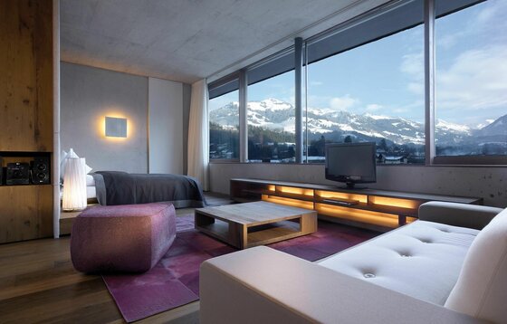 Hotel Schwarzer Adler Studio Modernes Hotelzimmer mit großem Panoramafenster und Blick auf verschneite Berge.
