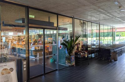 MPreis Jochbergerstraße Eingang Eingangsbereich eines MPreis Supermarktes mit Glasschiebetüren und Einkaufswagen unter einem Betondach.