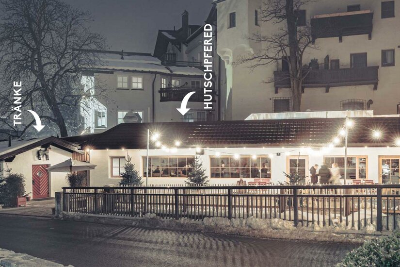 Hutschpferd Ein gemütliches Restaurant bei Nacht, beleuchtet von warmen Lichtern. Im Hintergrund sind einige Häuser und Bäume zu sehen.