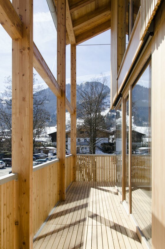 Balkon Haus Wegener Holzbalkon mit Blick auf schneebedeckte Berge und ein Dorf.