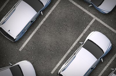 Hertz Eine Vogelperspektive auf einen Parkplatz mit mehreren weißen Autos. Die Parklücken sind deutlich sichtbar.