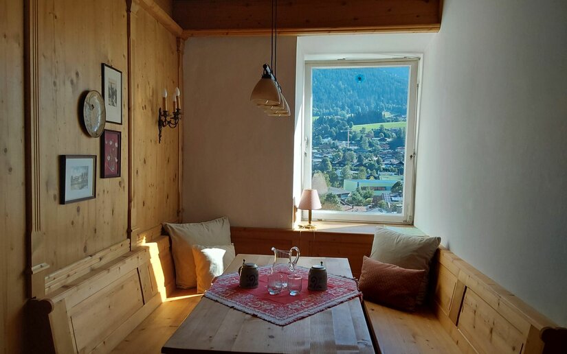 Sitzecke im Apartment City Kitz Rustikale Sitzecke aus Holz mit Esstisch und Blick aus dem Fenster auf eine Berglandschaft.