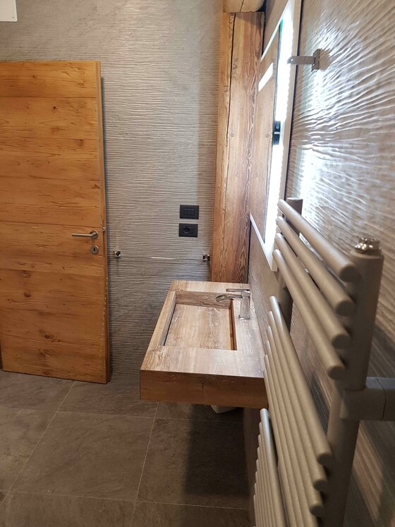 Modernes Badezimmer mit Holzwaschbecken, Holztür und Handtuchheizkörper.