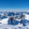 Eine Skitourengeherin steigt in den Südbergen bei Kitzbühel einen verschneiten Hang hinauf, umgeben von alpiner Berglandschaft und blauem Himmel.