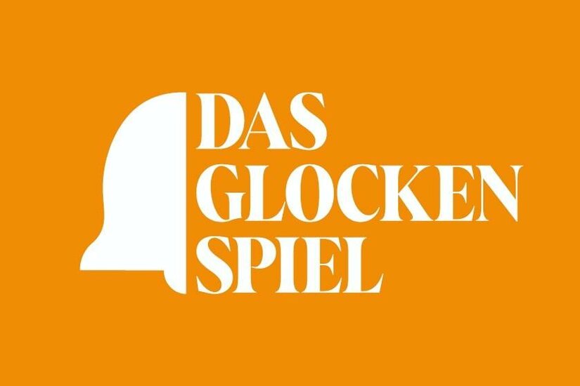 Logo Das Glockenspiel Weißes Logo mit Glockensymbol und dem Text DAS GLOCKENSPIEL auf orangefarbenem Hintergrund.
