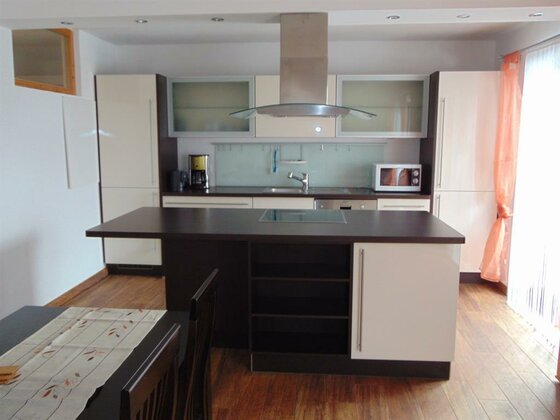 Küche Apartment 2 Moderne Einbauküche mit Kochinsel, dunkler Arbeitsplatte und hellen Fronten in einem Apartment.