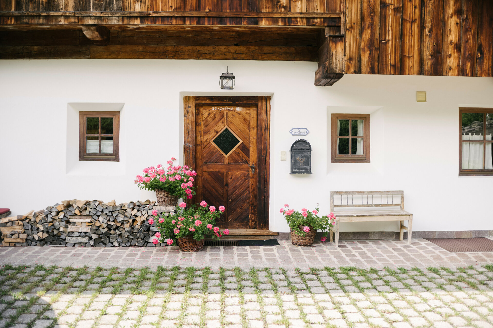 Die Fassade des Hauses zeigt eine einladende Atmosphäre mit einer Holzbank, Blumen und einem traditionellen Briefkasten.