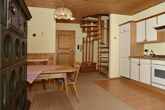 Wohnküche im Gasthof Alte Wacht Wohnküche mit Holztisch, Küchenzeile und einer hölzernen Wendeltreppe.