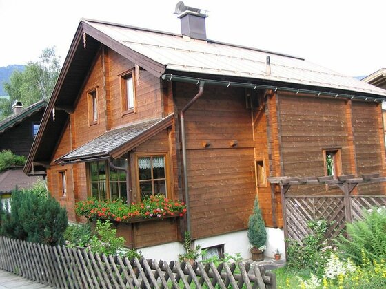 Haus Pirchner im Sommer Zweistöckiges Holzhaus mit Satteldach, Blumenkästen und Holzzaun im Vordergrund.