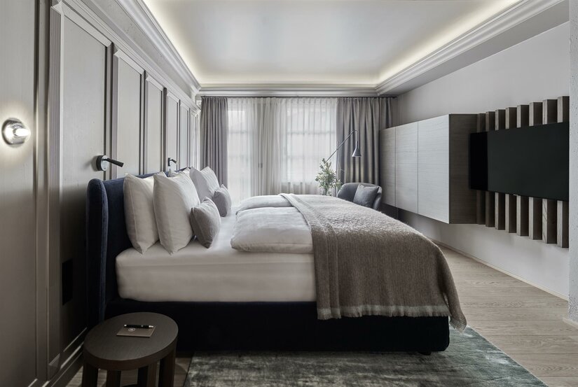 Modernes Hotelzimmer mit Doppelbett, Wandpaneelen und Fernseher.