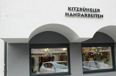 Außenansicht eines Ladengeschäfts mit der Aufschrift Kitzbüheler Handarbeiten über zwei Schaufenstern.