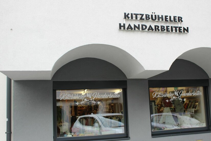 Kitzbüheler Handarbeiten Außenansicht eines Ladengeschäfts mit der Aufschrift Kitzbüheler Handarbeiten über zwei Schaufenstern.