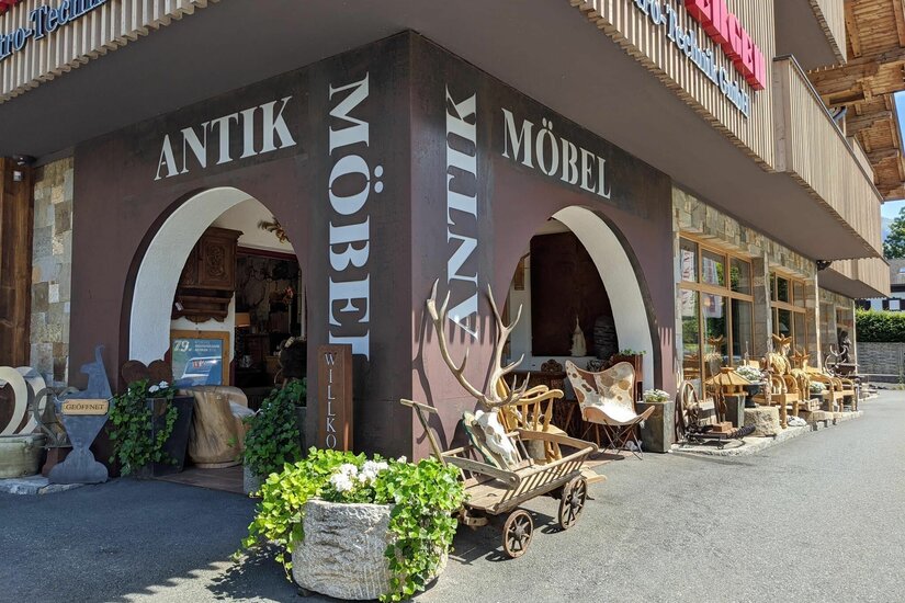 Antikmöbel Obermoser Eingangsbereich eines Geschäfts für Antikmöbel mit Rundbögen, Holzkarren und Geweihen.