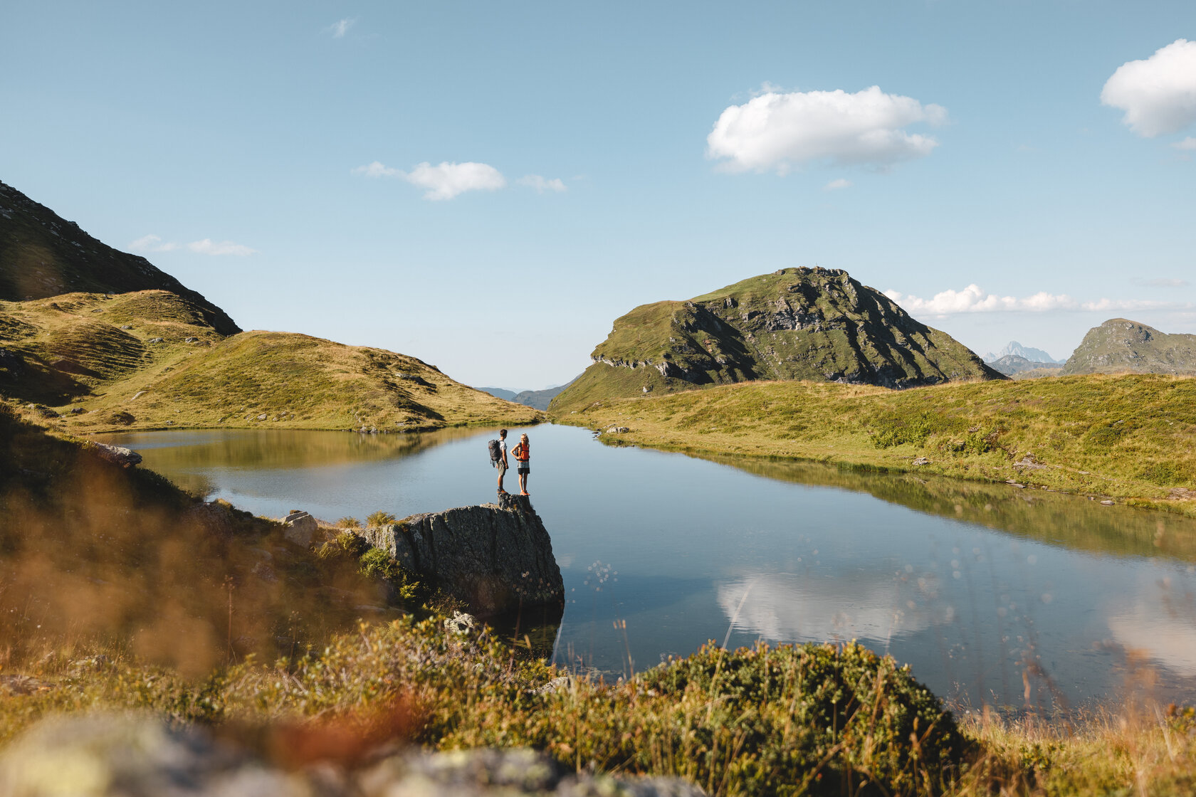 A mountain lake surrounded by grass, with a peak in the background