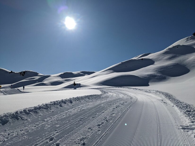 Horn Winterwanderroute im Schnee Präparierter Winterwanderweg in einer verschneiten Hügellandschaft unter blauem Himmel mit Sonnenschein.