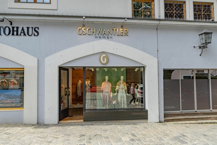 Modeboutique Gschwantler Außenansicht der Modeboutique Gschwantler mit Schaufensterpuppen in einem hellen Steingebäude.