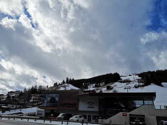 Talstation Wagstättbahn Jochberg Moderne Talstation der Wagstättbahn in Jochberg vor verschneitem Berghang unter bewölktem Himmel.