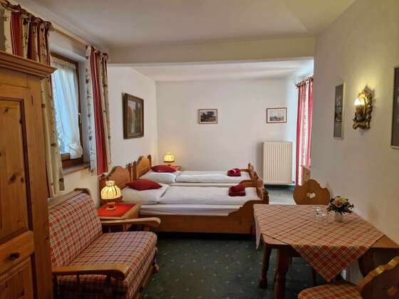 Gästezimmer Pension Alpenrose Gästezimmer mit zwei Einzelbetten aus Holz, einer Sitzecke und einem Tisch mit karierter Decke.