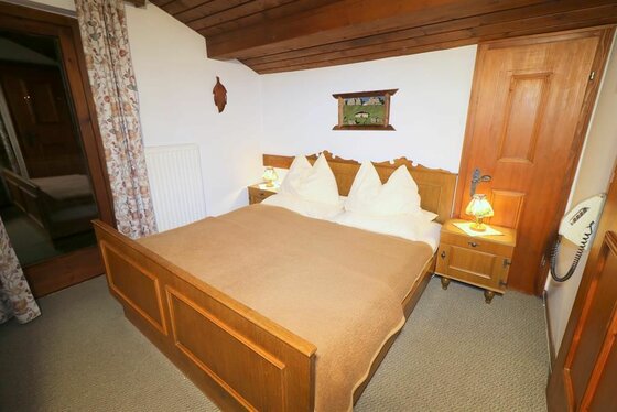 Schlafzimmer im Landhaus Eva Rustikales Doppelbett aus Holz in einem Zimmer mit Dachschräge und Nachttischen.