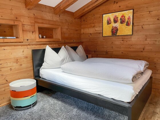 Schlafzimmer der kleinen Wohnung Schlafzimmer mit Doppelbett in einer holzgetäfelten Hütte.