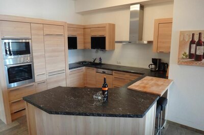 Moderne Einbauküche in Holzoptik mit dunkler Arbeitsplatte und Kücheninsel.