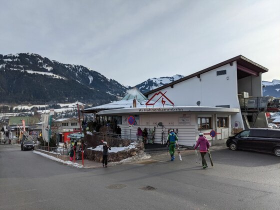 Talstation Hahnenkammbahn Talstation der Hahnenkammbahn mit Skifahrern vor schneebedeckten Bergen.
