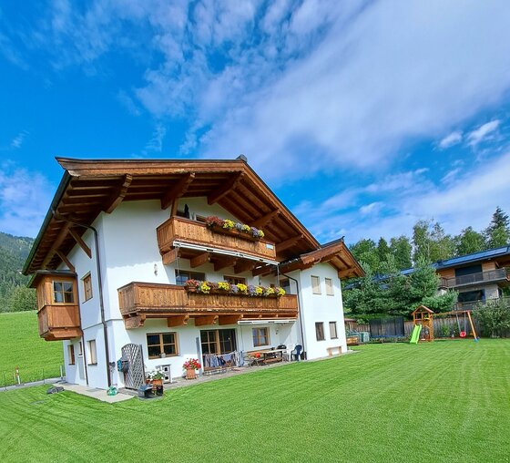 Ein schönes, traditionelles Haus mit Holzbalkonen in einer grünen Umgebung.