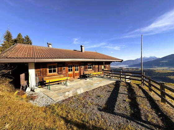 Eine gemütliche Hütte mit Holzverkleidung und großen Fenstern. Die Terrasse bietet einen Blick auf die Berglandschaft und die umliegende Natur.