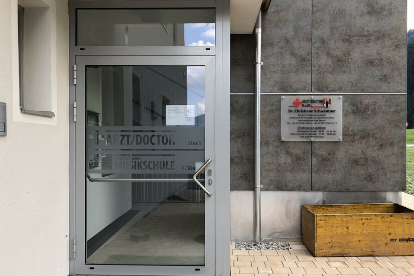 Eingang Dr. Schwentner Eingangsbereich einer Arztpraxis mit Glastür und Hinweisschild an der Fassade.