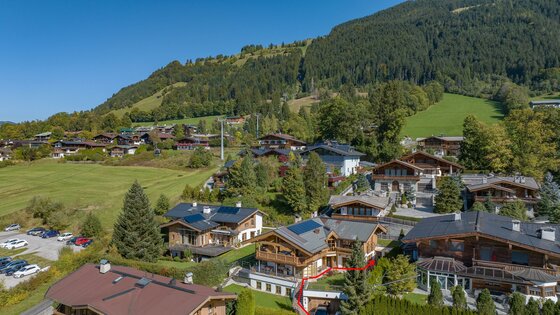 Chalet Kitzbühelblick Zugang Luftaufnahme von Chalets in Hanglage mit einem bewaldeten Berg im Hintergrund.