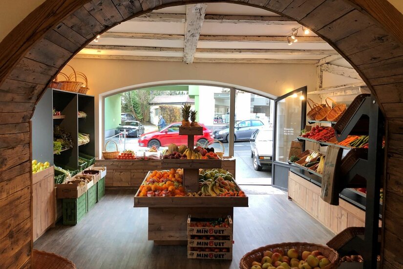 Özer Obst und Gemüse Innenansicht eines Obst- und Gemüseladens mit Holzregalen und Auslagen unter einem Holzbogen.