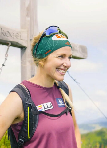 Lisa Hauser vor einem Gipfelkreuz auf dem Berg