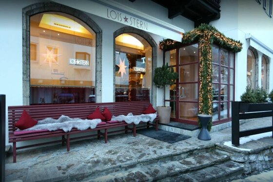 Außenansicht des Restaurants Lois Stern mit einer Holzbank, Fellen und Weihnachtsdekoration.