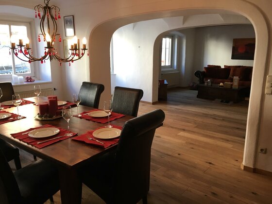 Essbereich im Appartement Gedeckter Holztisch mit dunklen Lederstühlen in einem Raum mit Rundbögen und Parkettboden.