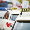 Zwei Taxis stehen an einer Straßenecke, während ein blauer Bus im Hintergrund vorbeifährt, was eine belebte Stadtatmosphäre schafft.
