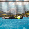 Ein Padel-Platz mit blauem Belag, auf dem ein Schläger und ein Ball liegen, in Kitzbühel.