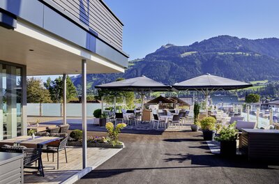 Terrasse Aktivhotel Schweizerhof Außenterrasse des Aktivhotel Schweizerhof mit Tischen, Sonnenschirmen und Blick auf die Kitzbüheler Alpen.