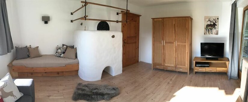 Ein gemütlicher Raum mit einem Holztag, einem Kamin und einem Fernseher. Die Wände sind hell und die Möbel haben einen rustikalen Stil.