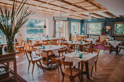 Restaurant Seebichl Innenansicht Innenansicht eines Restaurants mit Holztischen, Stühlen, Parkettboden und großen Fenstern.