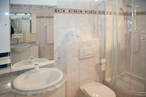 Badezimmer im Egger Studio Badezimmer mit weißem Waschbecken, Toilette und einer Dusche mit Glaswand.